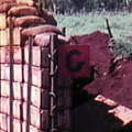 Entrance to a wooden military structure dug into red soil with green jungle in the background