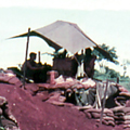 Military structures set amongst red soil with green grass in the background