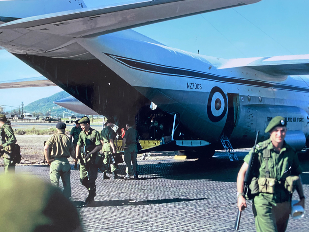 Soldiers in green uniforms exit aeroplane.