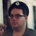 Malcolm Knox Colour photograph of man in uniform walking inside a building surrounded by Vietnamese people.