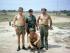 Four men, three shirtless, grouped together in military uniform.