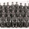 Group of men in military uniform sitting and standing in rows.