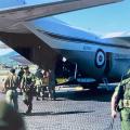 Soldiers in green uniforms exit aeroplane.