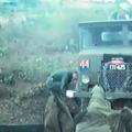 Man in green uniform crouching down next to green coloured truck