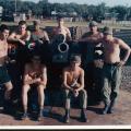 Group of men in khaki military uniform standing and kneeling around artillery gun.