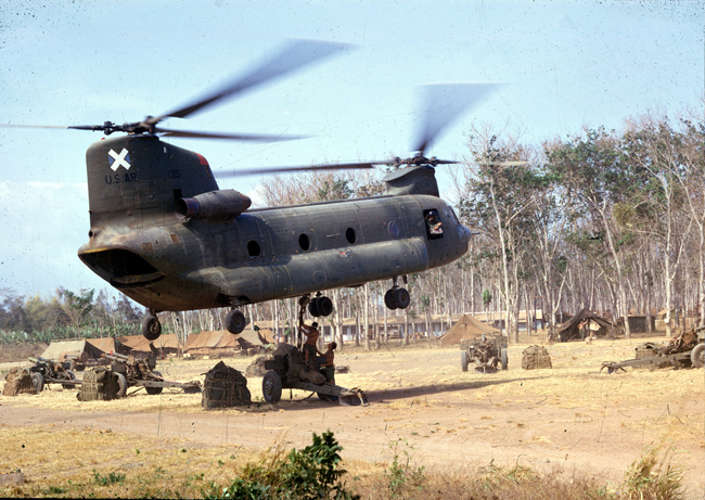 Chinook helicopter moving Howitzer artillery, circa 1968